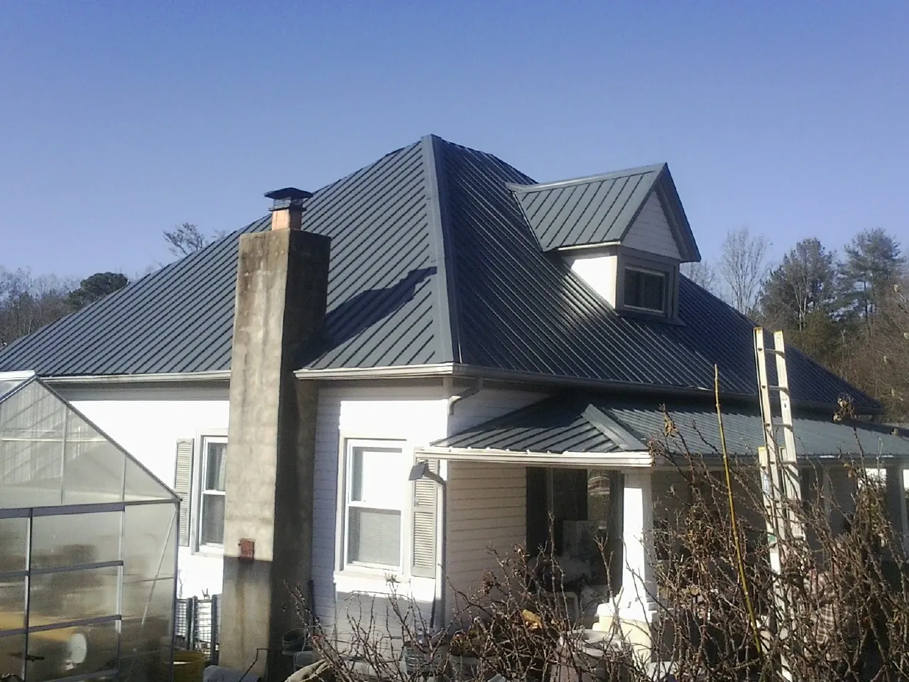 Dark blue standing seam metal roof on a white farmhouse with dormer — Slate & Tile Roof Repair by Roofing Brothers in Montpelier Station