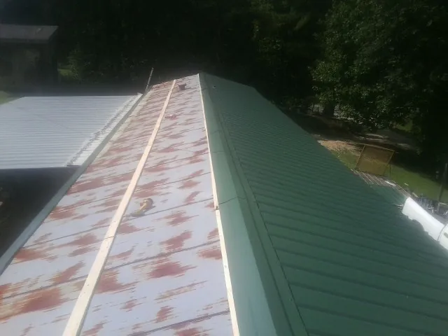 Old rusted panels beside newly installed green metal roofing — Wind Damage Roof Repair by Roofing Brothers in Montpelier Station
