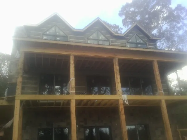 Dormers and porch framing on a large log home under construction — Roof Coating work by our crew in Montpelier Station