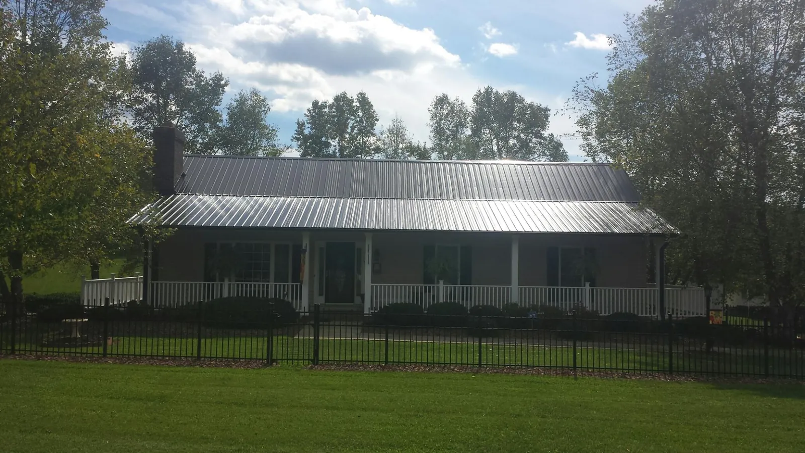 Gray metal roof on a brick ranch with a full width front porch — Gutter Guard Installation work by our crew in Montpelier Station