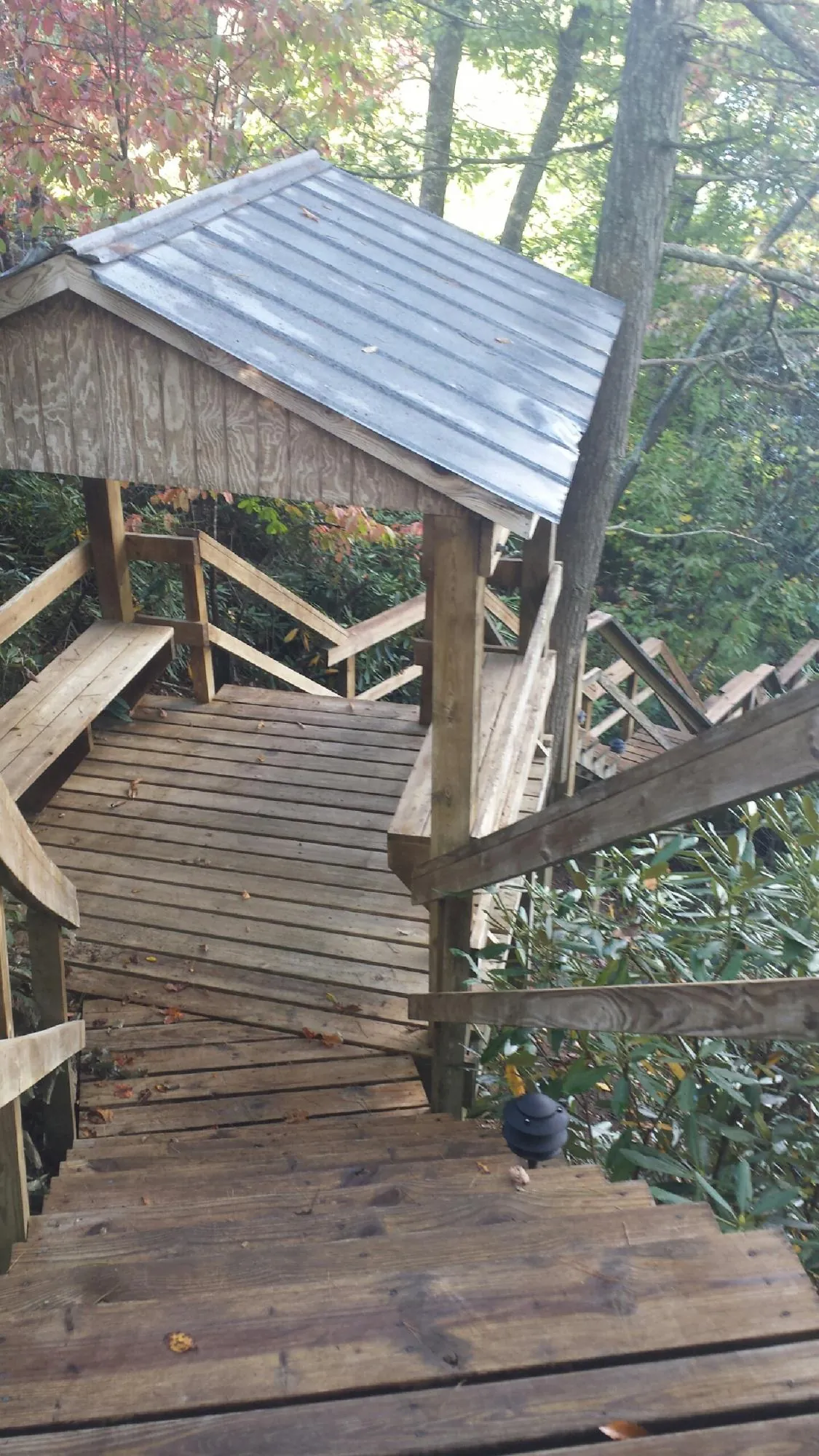 Metal roofed shelter over wooden steps on a wooded walkway — Skylight Repair & Installation work by our crew in Montpelier Station
