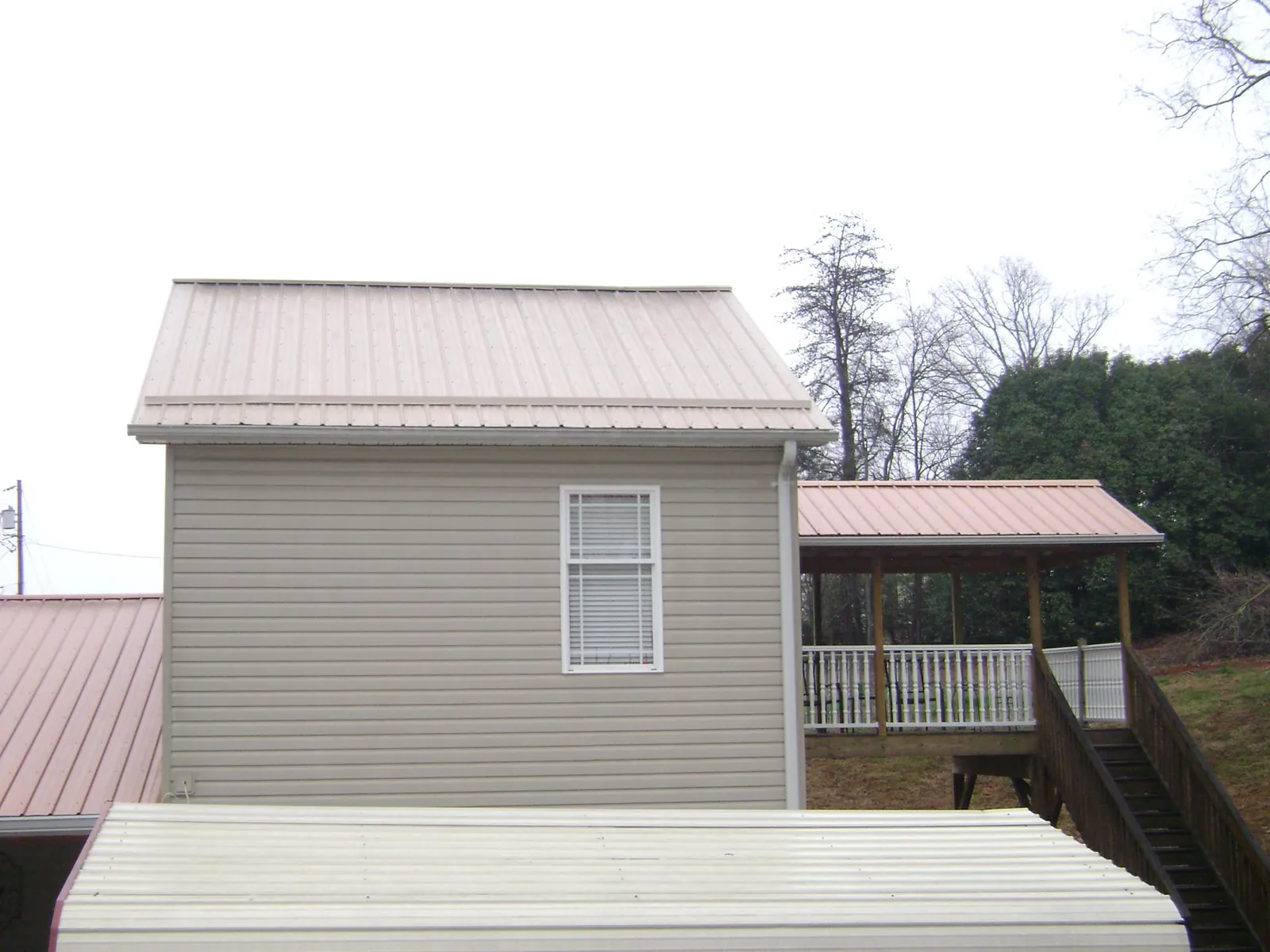 Tan metal roofs on a two story addition and attached porch, from a Roof Replacement job in Montpelier Station