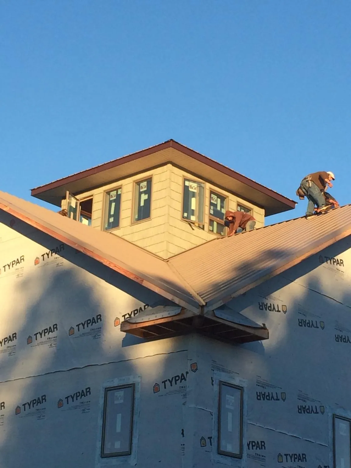 Roofers working around a rooftop cupola on a new metal roof at sunset — Roof Waterproofing in Montpelier Station by Roofing Brothers